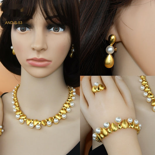 Women's four-piece jewelry set with matte gold teardrop links and white pearls, including a necklace, earrings, ring, and bracelet.