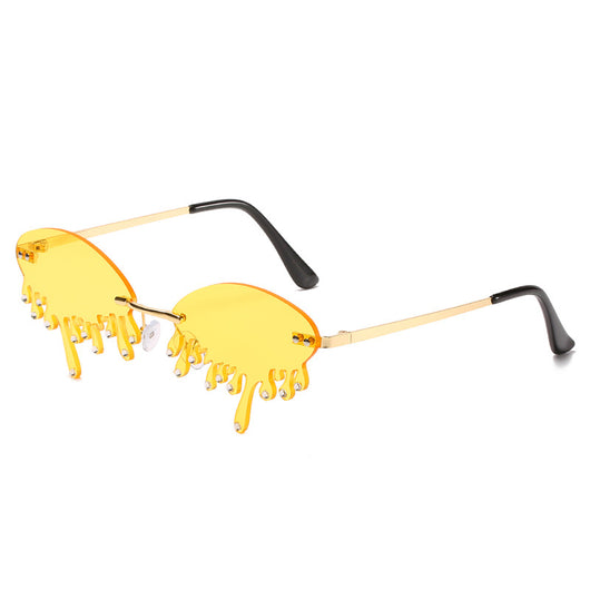 Rimless sunglasses with dark gray dripping liquid-shaped lenses, silver studs, and gold metal frames.