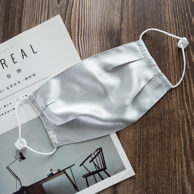 Light pink double layer silk face mask with adjustable white ear loops on an open magazine. - Image 3