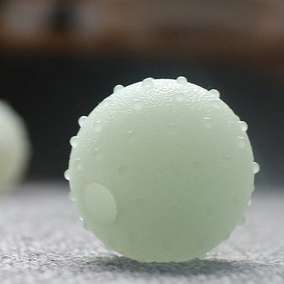 Interactive pet glow ball, off-white in daylight and glowing green in the evening, with a textured surface. - Image 5