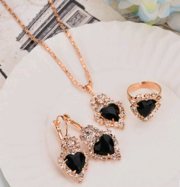 Rose gold-toned necklace, earrings, and ring set with large oval clear gemstones surrounded by smaller stones. - Image 15