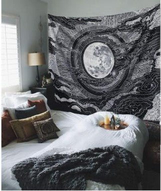 Black and white Indian mandala tapestry with a detailed moon and celestial design, hung above a bed.