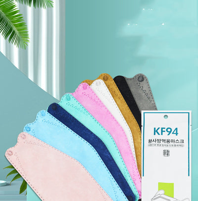 A fan of multi-colored KF94 fish-shaped masks in pink, blue, teal, white, gold, black, and grey, next to a packaged mask.