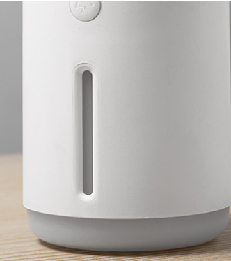 Porcelain white cylindrical humidifier emitting jellyfish-shaped mist, sitting on a round base against a split teal and dark green background. - Image 13