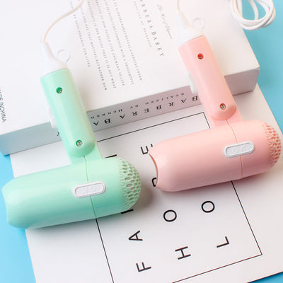 Light blue foldable hair dryer with a cartoon pig design, white power switch, and hanging loop. - Image 4