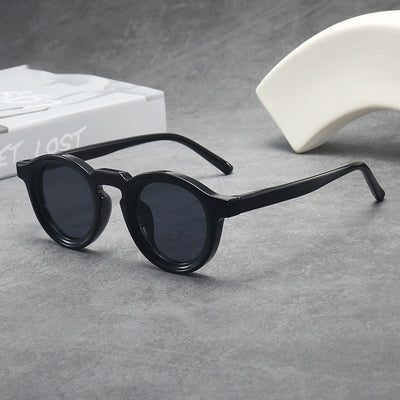 Vintage round frame sunglasses with black frames and pink lenses on a gray surface. - Image 3