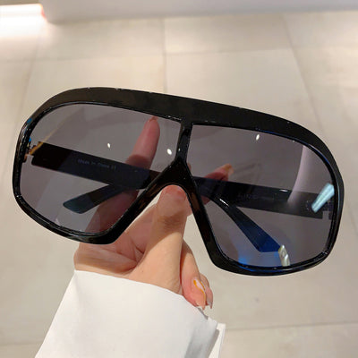 Oversized women's shield sunglasses with a tortoiseshell frame and brown-tinted lenses, held by a hand. - Image 6
