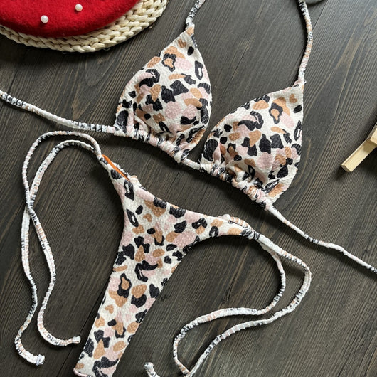 White textured bikini with red cherry print, featuring a triangle top and tie-side bottoms, on a woven mat. - Image 4