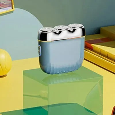 Orange mini electric shaver with three silver floating cutter heads, a blue power button, on a translucent orange block. - Image 6