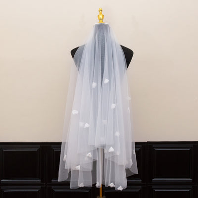 White and ivory sheer fabric swatches for a wedding veil displayed on green grass. - Image 3