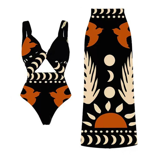Black one-piece swimsuit with an asymmetrical top and matching long skirt, featuring a tropical palm tree and bird print.