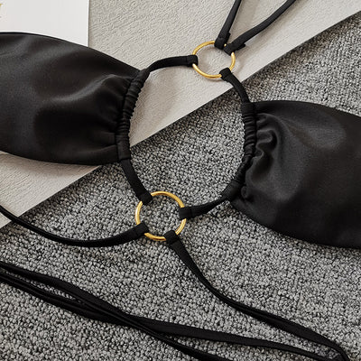 Solid black two-piece swimsuit set with a bandeau top, gold-tone O-rings, and tie straps, paired with matching thong bottoms. - Image 8