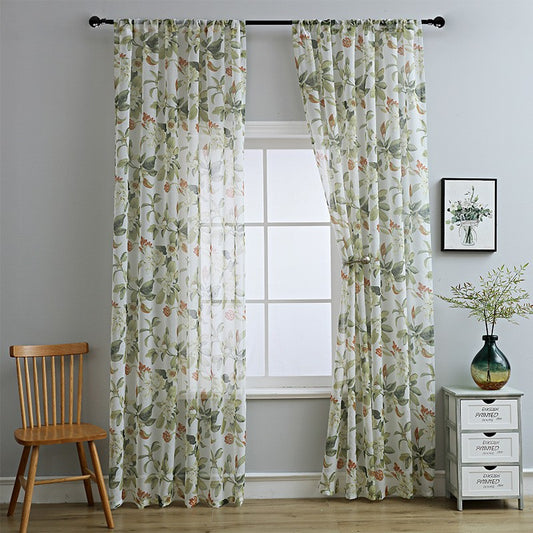 Dark gray semi-sheer curtains with a white and green floral pattern, hung on a black rod in a living room.