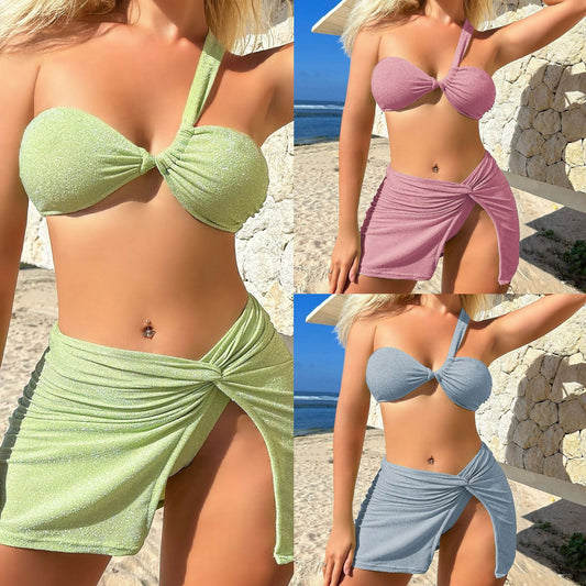 Pink shimmery three-piece swimsuit with a one-shoulder tube top, high-cut bikini bottom, and matching mini skirt.