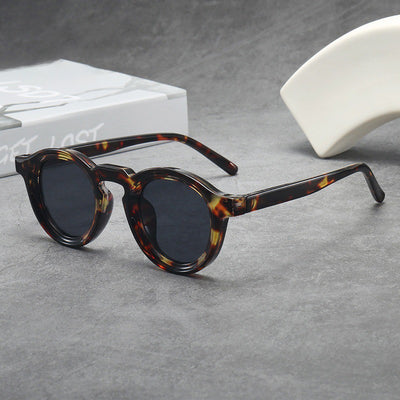 Vintage round frame sunglasses with black frames and pink lenses on a gray surface. - Image 6