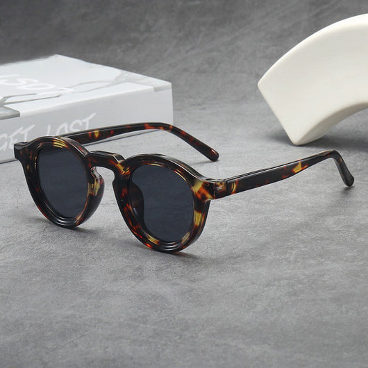 Vintage round frame sunglasses with black frames and pink lenses on a gray surface. - Image 6