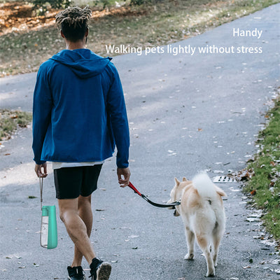 Yellow 450ml portable pet water bottle with a folding drinking trough and white wrist strap, on grass. - Image 14