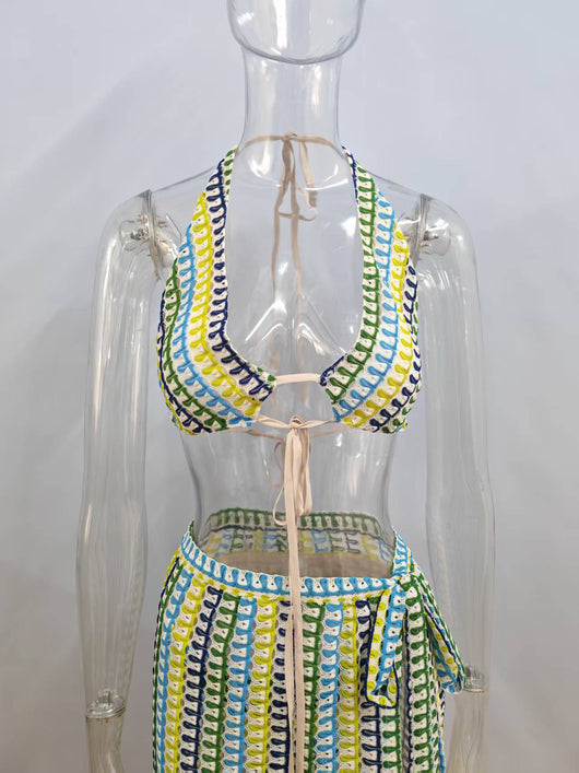Woman in a blue, green, and yellow patterned halter bikini top and matching flowy sarong on a sunny beach. - Image 13