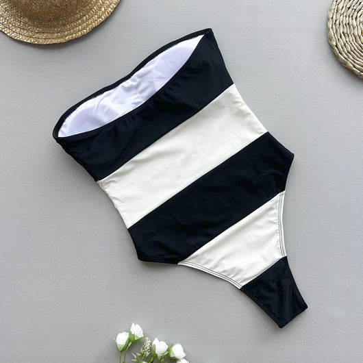Women's black and white striped strapless one-piece swimsuit with a high-cut leg, modeled outdoors. - Image 4