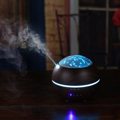 Mini wood grain aroma diffuser and humidifier with a starry night light projector, emitting mist and glowing purple.