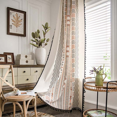 Boho cream cotton and linen curtain with tribal print in black and orange, featuring black fringe tassels.