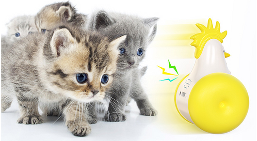 White and yellow chicken-shaped tumbler cat toy with a laser pointer, being played with by two orange tabby cats. - Image 16