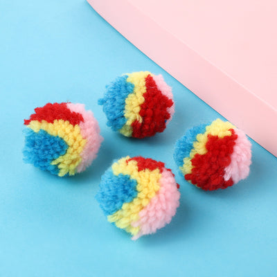 A hand holds a fluffy rainbow pom-pom ball toy, with another colorful ball in the background. - Image 10