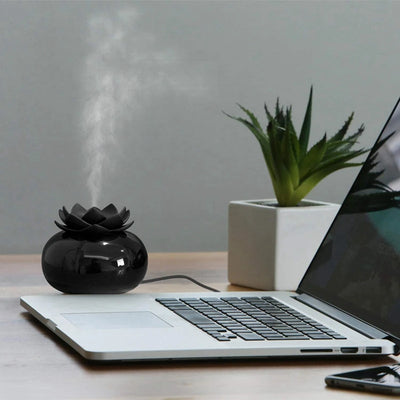 Black spherical aromatherapy humidifier with a lotus flower top, emitting mist, sitting on a gold decorative doily. - Image 10
