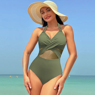 Woman in a green halter-neck one-piece swimsuit with cross-strap design and mesh cutouts, on a beach. - Image 6