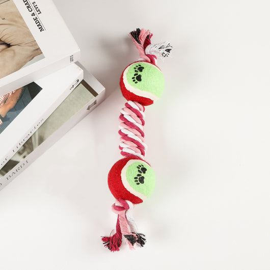 Red, pink, and white braided cotton rope dog toy with a green and red tennis ball featuring black paw prints. - Image 4