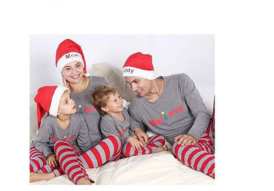Family of four in matching grey long-sleeve tops and red striped pants, posing in a festive holiday setting. - Image 3