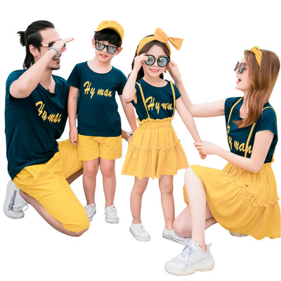 Family of four in matching dark blue short-sleeved tops with yellow text and yellow bottoms, posing outdoors. - Image 13