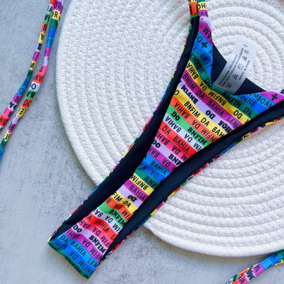 Women's multicolor letter printed lace-up bikini suit with triangle top and thong bottom, displayed on a white mat. - Image 15