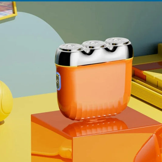 Orange mini electric shaver with three silver floating cutter heads, a blue power button, on a translucent orange block. - Image 2