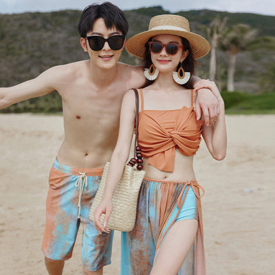 Men's or unisex swim shorts with a blue, orange, and brown abstract tie-dye print, featuring a drawstring waist and side pockets.
