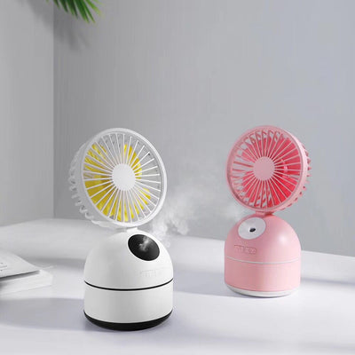Dark grey fan humidifier with a round fan head and spherical base, emitting mist, on a white desk. - Image 4
