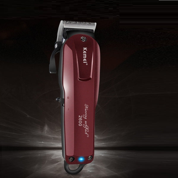 Kemei electric hair clipper in metallic burgundy with four guide combs, power adapter, cleaning brush, and oil bottle.