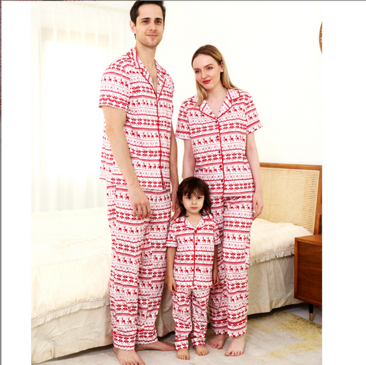 Woman wearing a red and white fair isle reindeer print short-sleeve pajama set with long pants in a bedroom. - Image 3