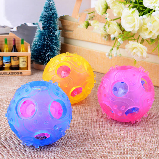 Three translucent hollow toy balls in pink, blue, and yellow, with textured surfaces and internal components.