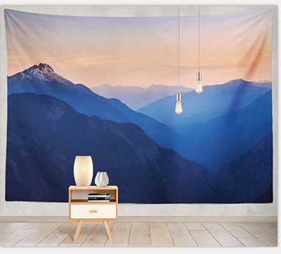 Digital print tapestry featuring a serene mountain landscape with layers of blue peaks under an orange and pink sky.