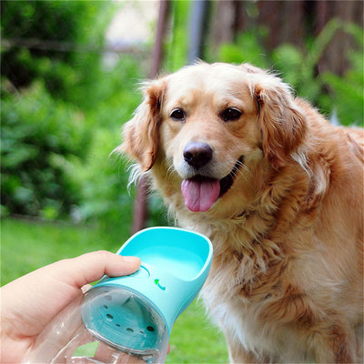 White portable pet water bottle with a clear reservoir and built-in drinking bowl, shown in a bag.