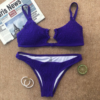 Red pleated cutout bikini set with a triangle top and thong bottom, displayed with yellow sunglasses and white flowers. - Image 8
