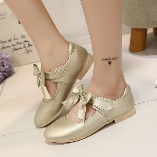Gold Mary Jane shoes for girls with a large decorative bow on the strap and a low, comfortable heel.
