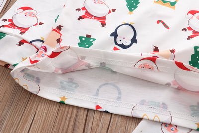 Family of four wearing matching white Christmas pajamas with Santa, penguin, reindeer, and tree print. - Image 14