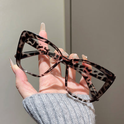 Clear large-frame square glasses held by a hand in a grey knitted sweater, showcasing the transparent plastic frame. - Image 16