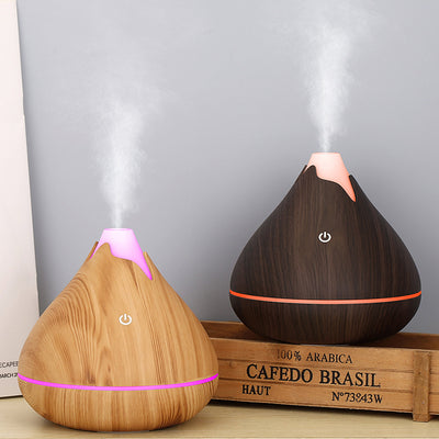 Teardrop-shaped aromatherapy humidifier with light wood grain finish, emitting mist and glowing with purple LED light. - Image 6