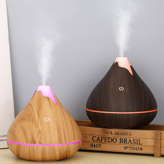 Teardrop-shaped aromatherapy humidifier with light wood grain finish, emitting mist and glowing with purple LED light. - Image 6