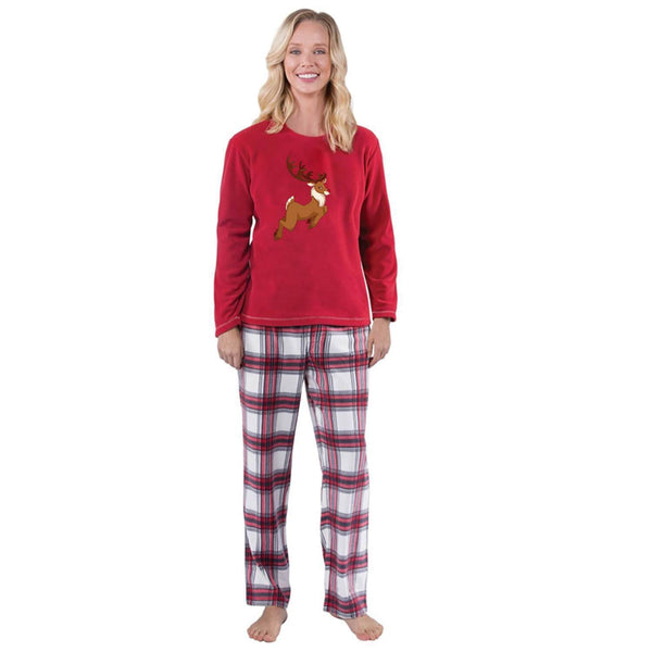 Family of five and a dog wearing matching red long-sleeve reindeer print tops and red and white plaid pajama pants.