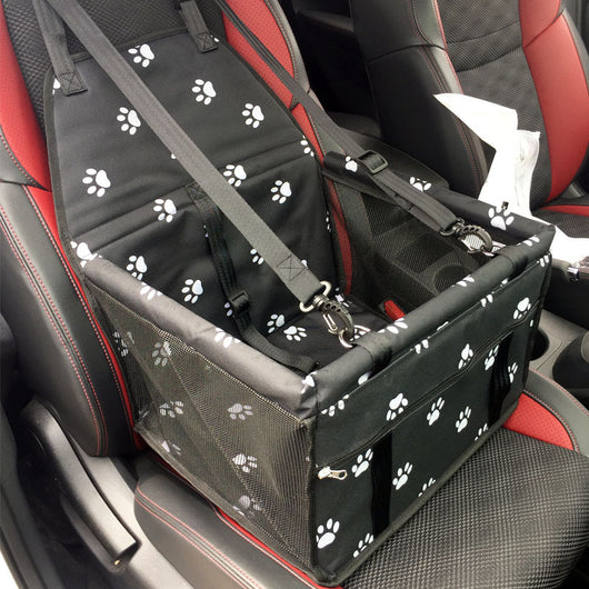 Light grey pet car booster seat with black mesh sides and adjustable straps, installed on a black and red car seat.