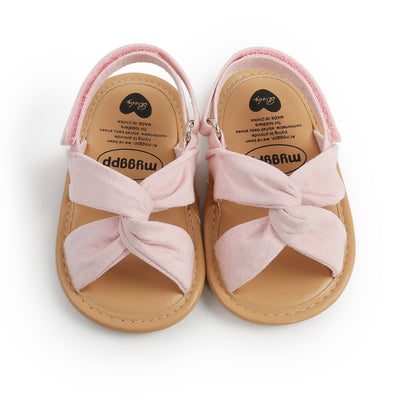 Black baby sandals with knotted cross straps and a matching black floral headband on a white background. - Image 8